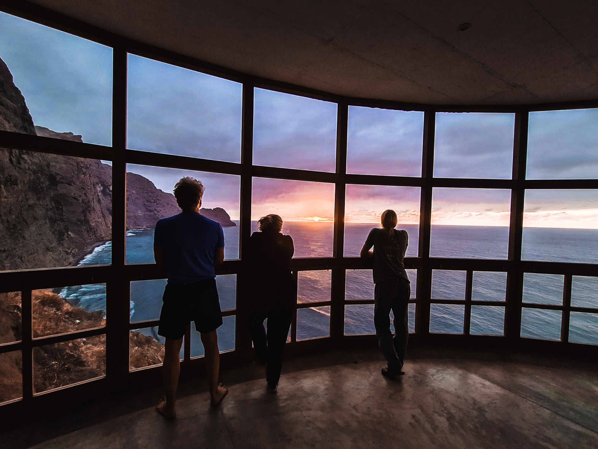 drei Menschen schauen einen Sonnenuntergang an